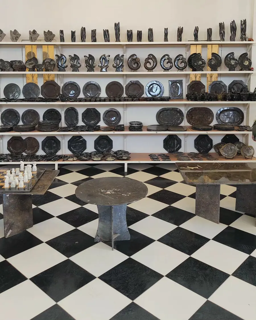 Étagères d'un magasin de fossiles au Maroc avec orthocères polis, assiettes et tables en pierre