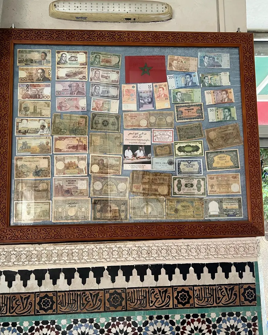 Cuadro con billetes marroquíes antiguos en francos y dírhams en la pared de Chez Lamine, en Marrakech