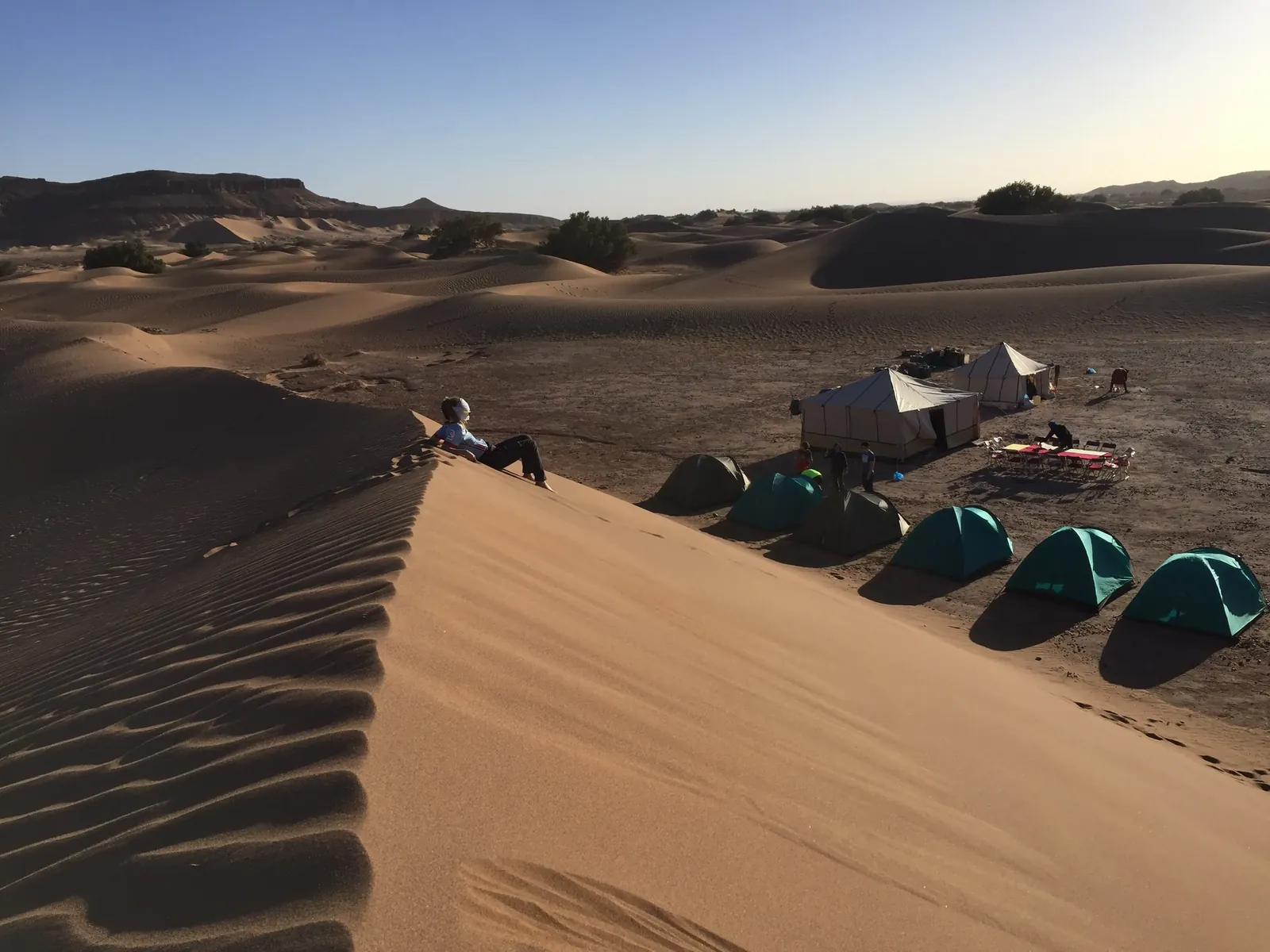 Campamento de trekking con tiendas de vivac y jaima al pie de una duna en el desierto de Marruecos