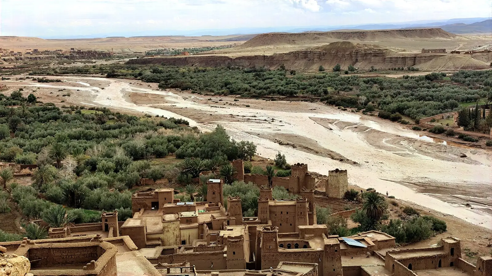 Casas y torres de tierra junto al palmeral y el ancho cauce de un río en el sur de Marruecos