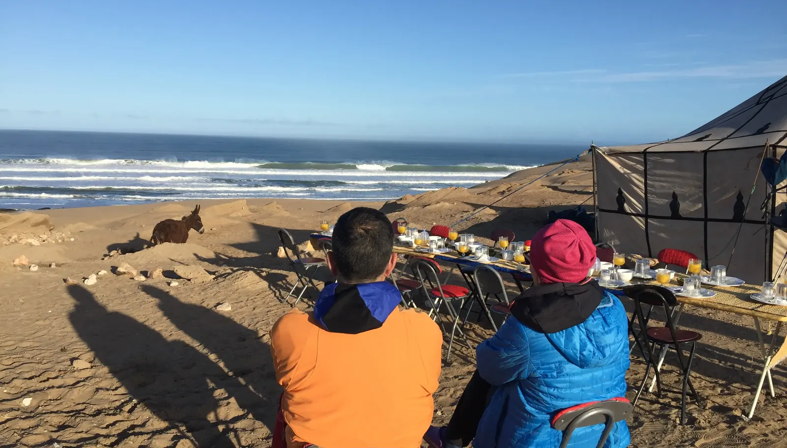 Dos senderistas desayunando en un campamento frente al océano Atlántico en la costa de Marruecos