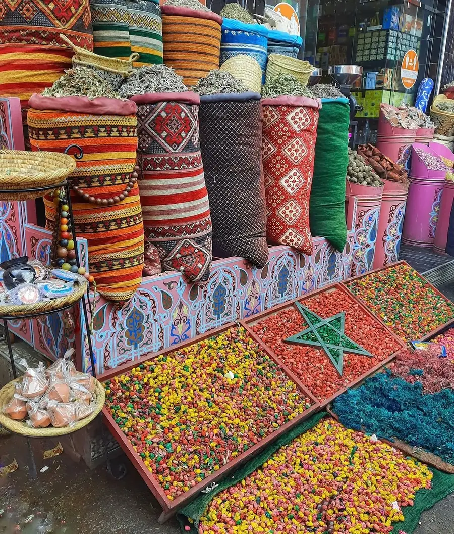 Étal d'herboriste dans un souk marocain avec des fleurs séchées colorées disposées comme le drapeau rouge à l'étoile verte