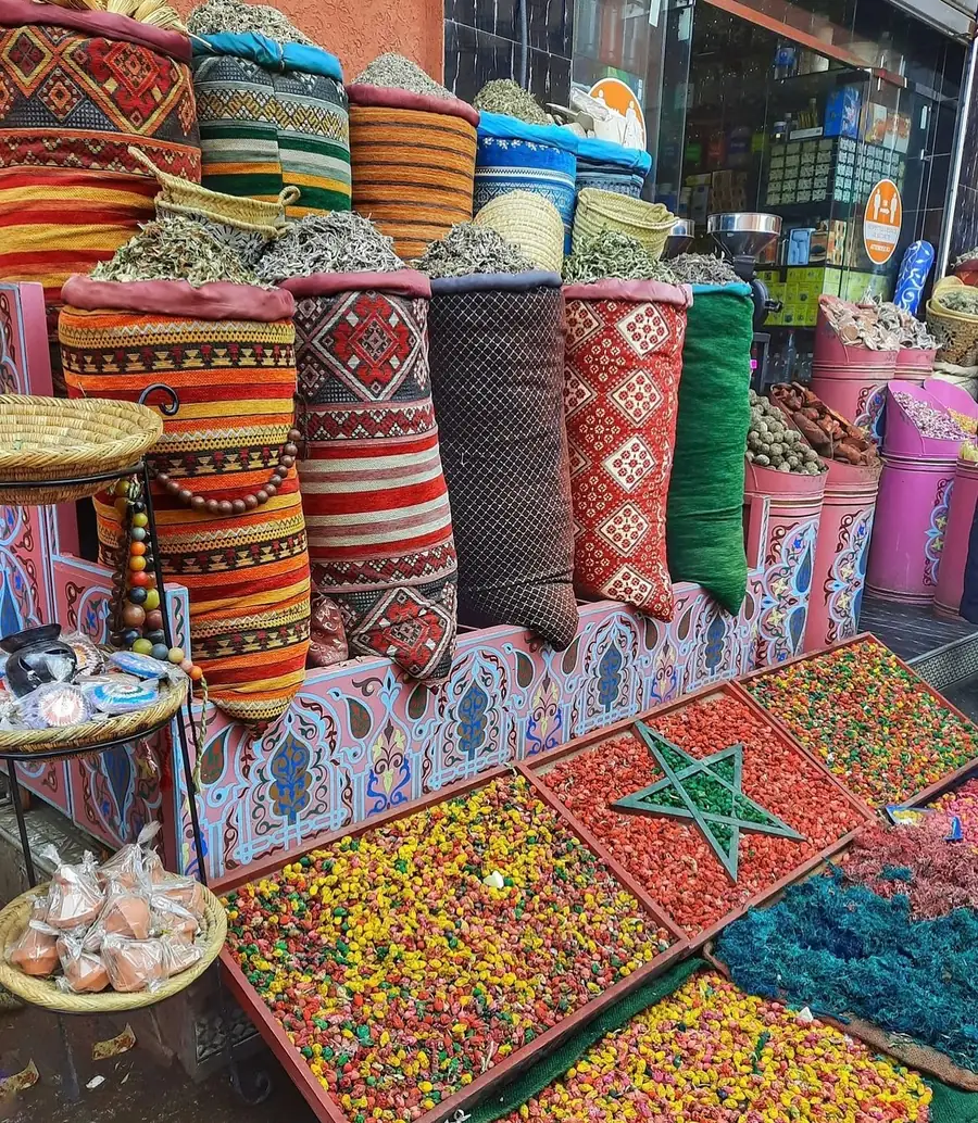 Puesto de herbolario en un zoco de Marruecos con flores secas de colores dispuestas como la bandera roja con la estrella verde