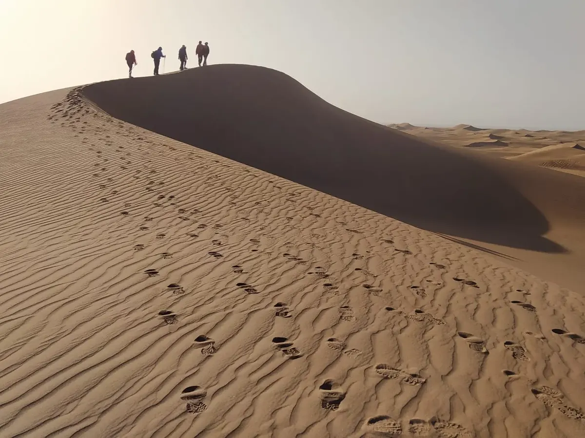 Huellas en la ladera de una duna que llevan hasta un grupo de senderistas en la cresta