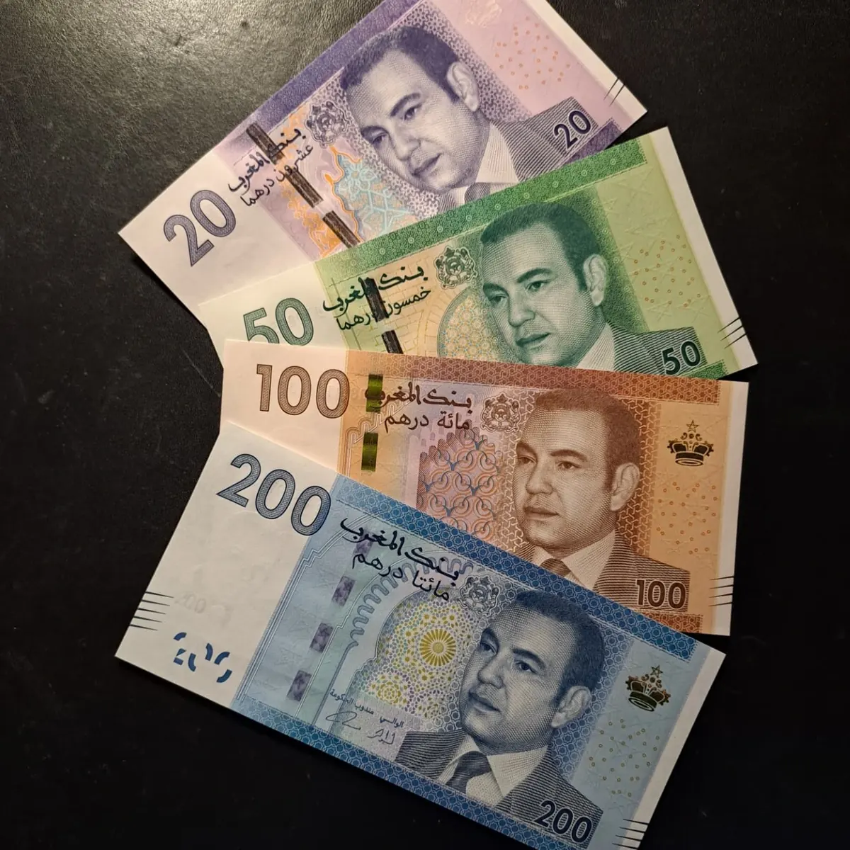 Moroccan 20, 50, 100 and 200 dirham banknotes from the 2012 series fanned out on a dark table