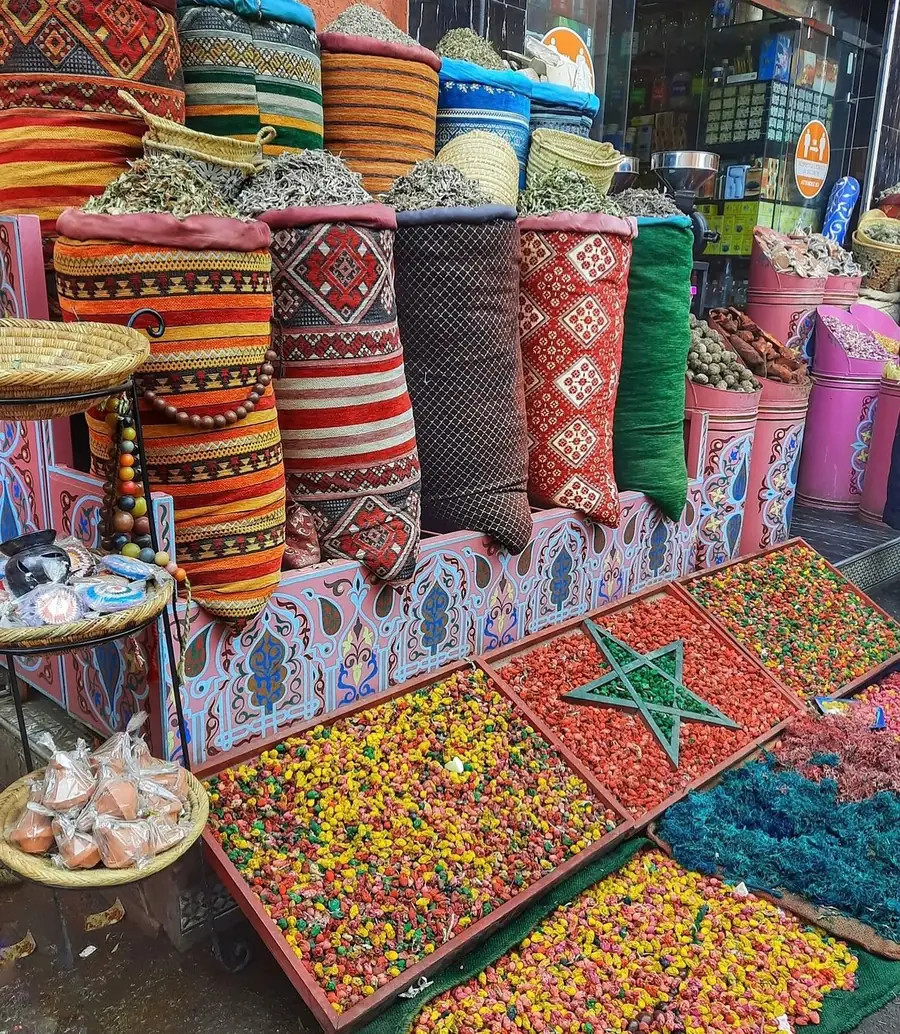 A herbalist's stall in a Moroccan souk with coloured potpourri arranged into a red field and a green star