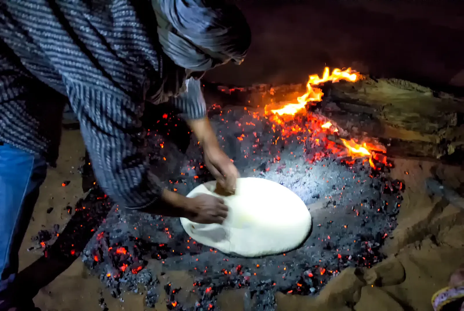 Preparación de la tagoula: la masa del pan bereber colocada sobre las brasas en el desierto
