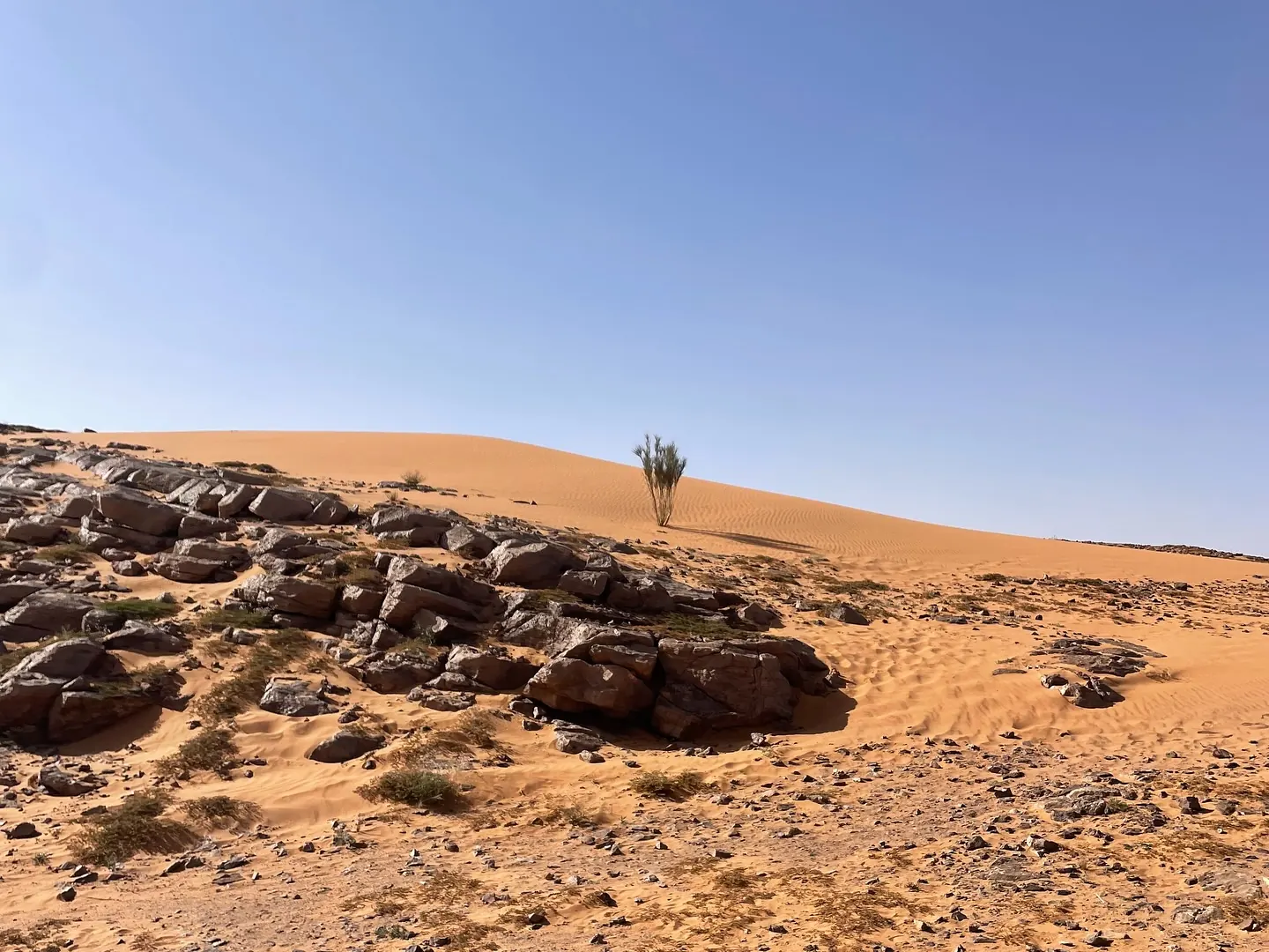 Afloramientos de roca oscura al pie de las dunas en el desierto del sureste de Marruecos