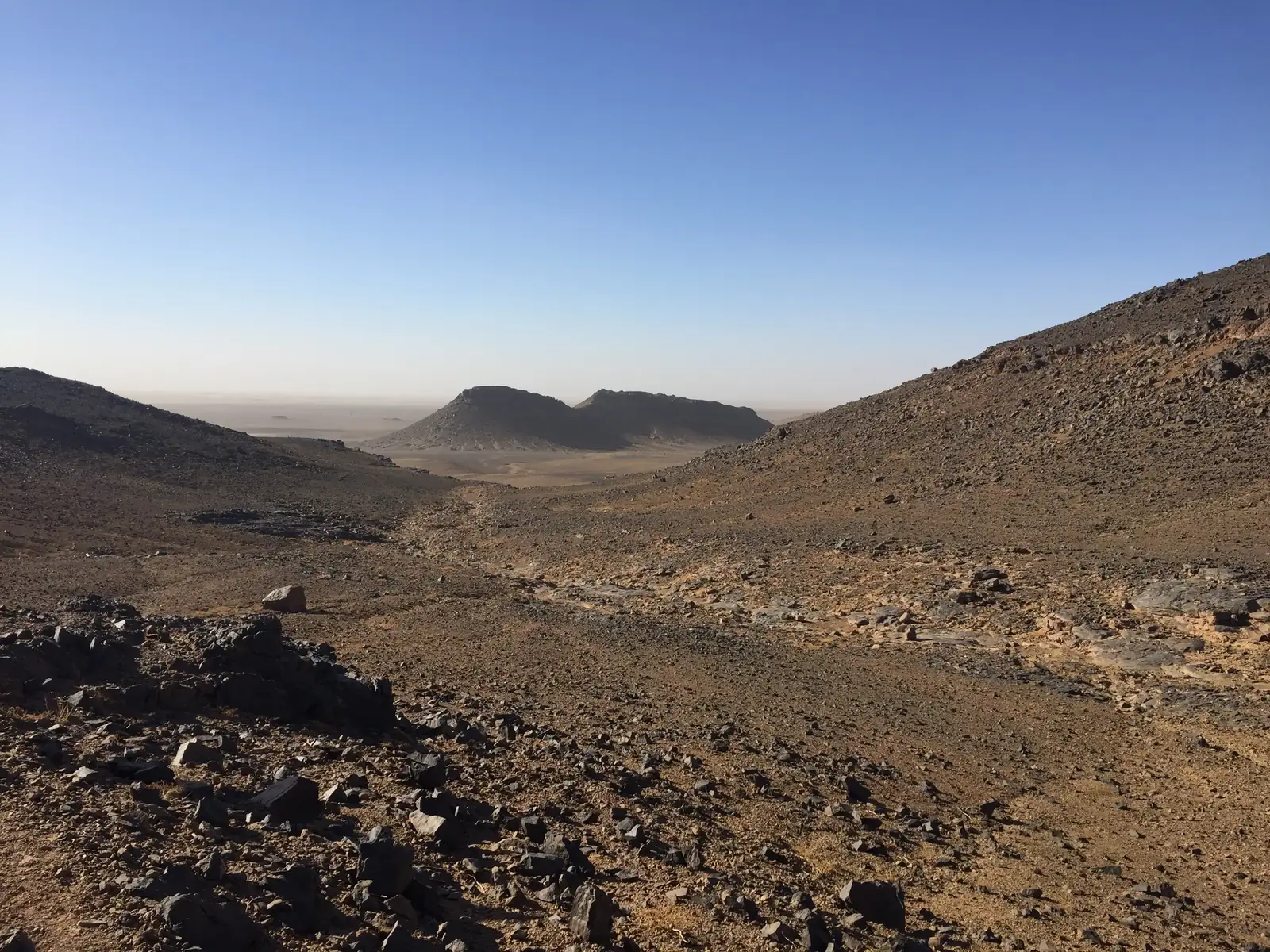 Rocky desert valley with stony slopes and flat-topped hills in southern Morocco