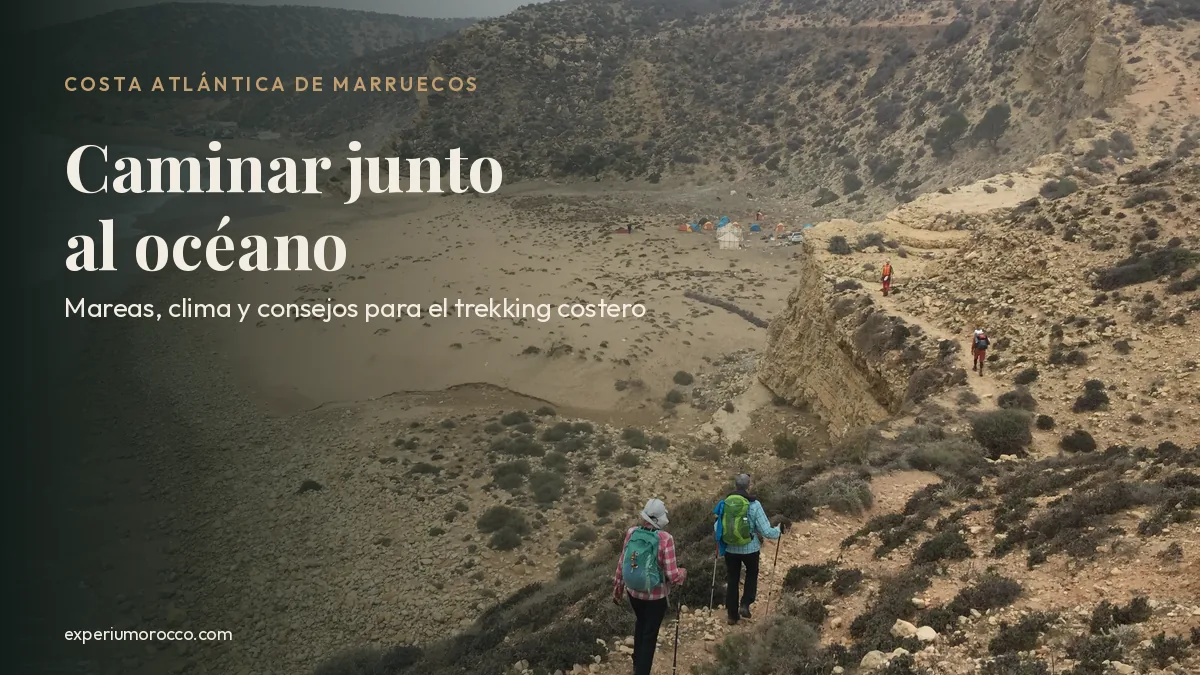 Senderistas bajando por un sendero de acantilado hacia una cala con campamento en la costa atlántica de Marruecos
