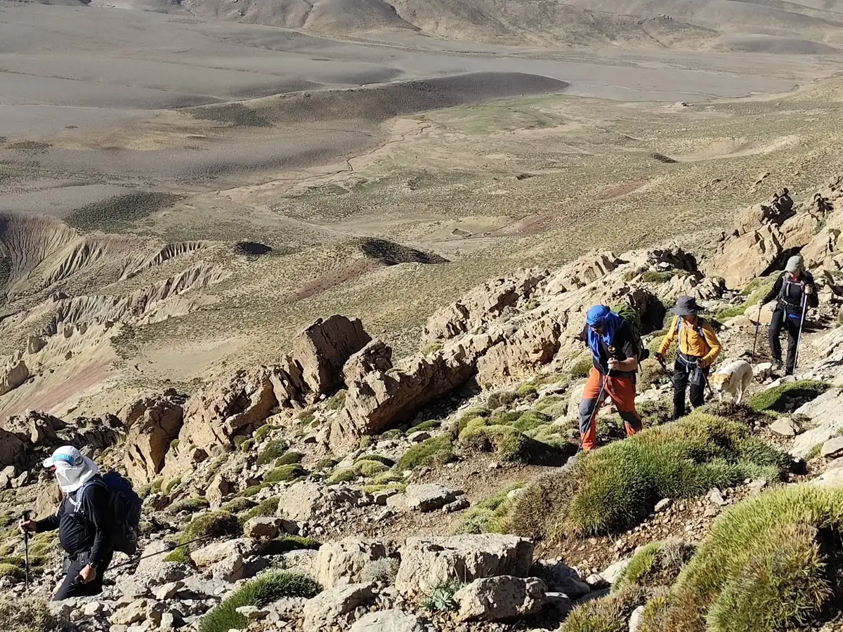 Group of trekkers climbing a rocky slope above a wide mountain valley in Morocco